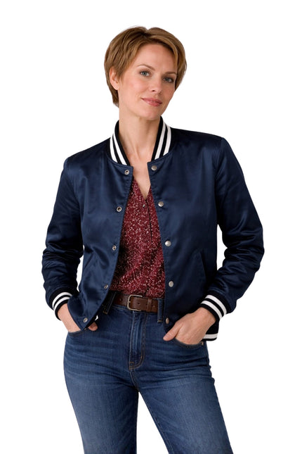 Woman wearing a navy blue jacket with white trim, red patterned shirt, and blue jeans on a white background