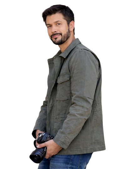 Man wearing a gray jacket holding a camera on a white background