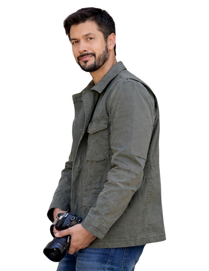 Man wearing a gray jacket holding a camera on a white background