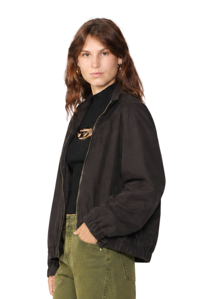 Woman wearing a black jacket over a black shirt with a logo, standing against a white background