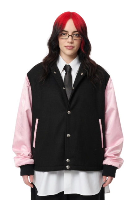 Person wearing a black and pink varsity jacket on a white background