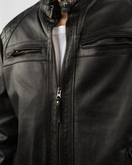 Close-up of a black leather jacket with zippers on a plain background