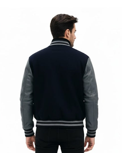 Man wearing a navy and gray varsity jacket on a white background