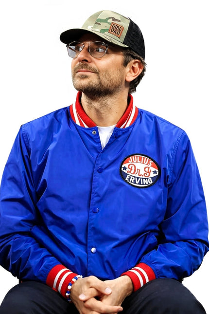 Man wearing a blue jacket with a logo, cap, and glasses on a white background