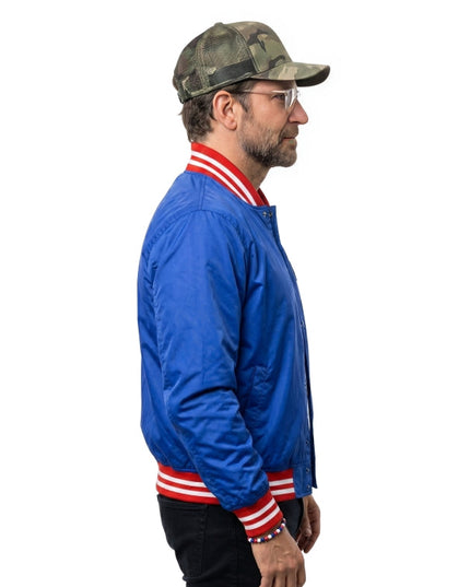 Man wearing a blue jacket with red and white stripes and a camouflage cap on a white background