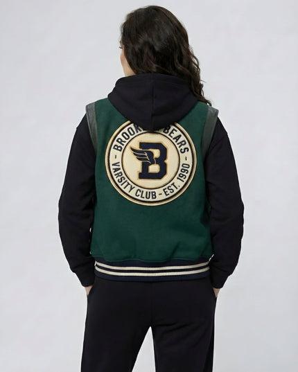Person wearing a green and black varsity jacket with a logo on the back against a white background