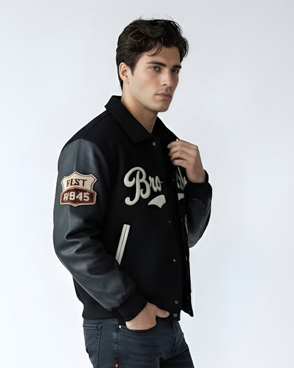 Man wearing a black varsity jacket with a logo and text on a white background