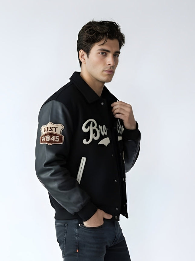 Man wearing a black varsity jacket with a logo and text on a white background