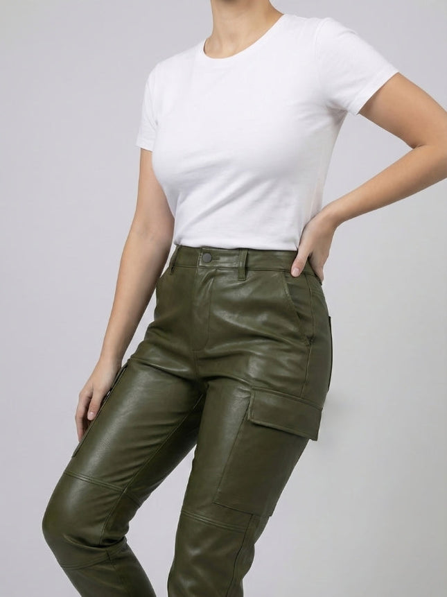 Person wearing green leather cargo pants and a white t-shirt on a plain background