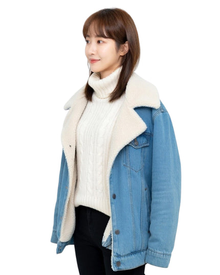 Woman wearing a blue denim jacket with white fur lining on a white background