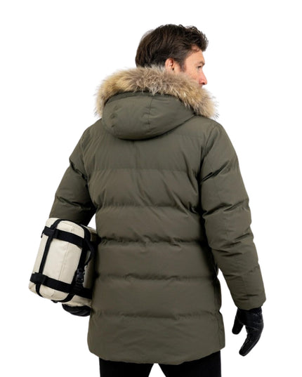 Person wearing a green winter coat with fur hood on a white background