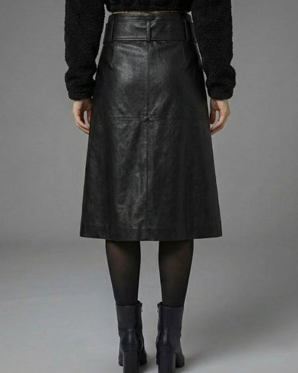 Person wearing a black leather skirt with a plain background