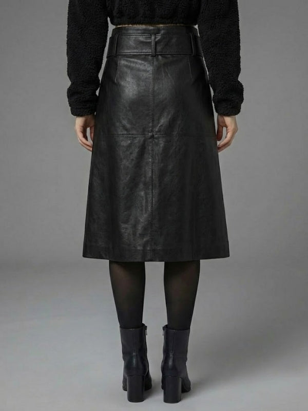 Person wearing a black leather skirt with a plain background