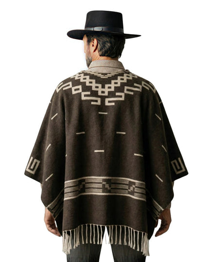 Person wearing a brown patterned poncho and black hat on a white background