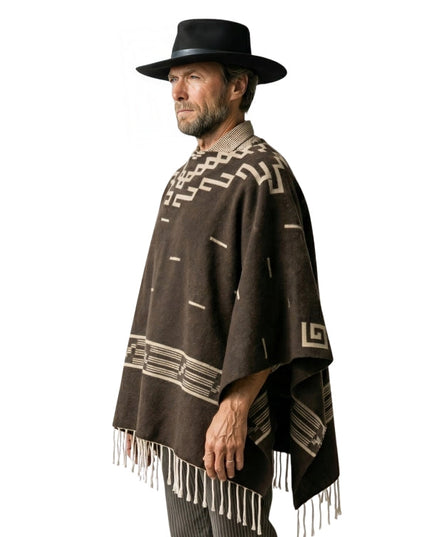 Man wearing a brown poncho with white patterns and fringes, and a black hat on a white background.