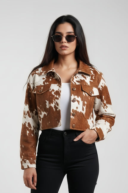 Woman wearing a brown and white cow print jacket on a plain background