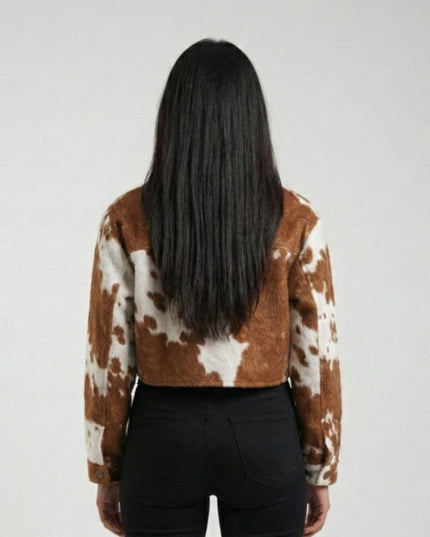 Person wearing a brown and white cow print jacket on a plain background