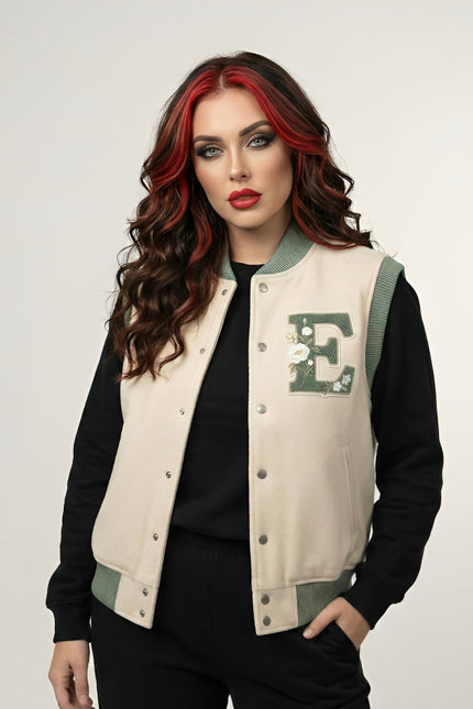 Woman wearing a beige letterman jacket with a green 'E' emblem on a white background
