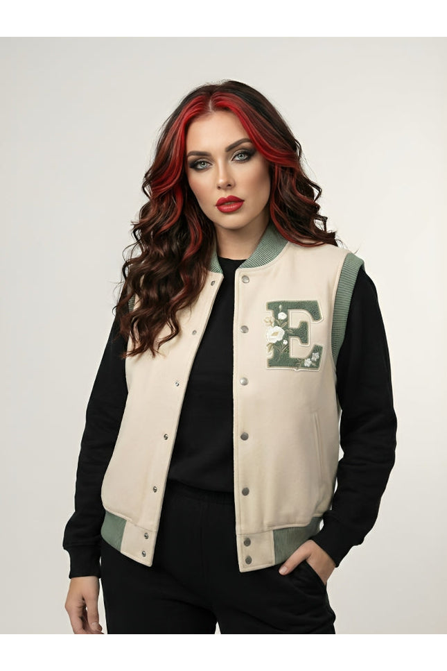 Woman wearing a beige letterman jacket with a green 'E' emblem on a white background