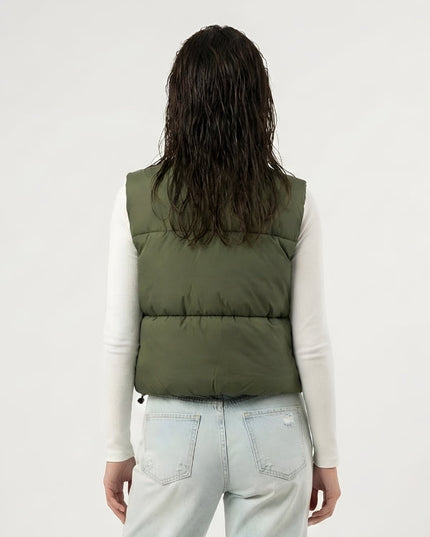 Person wearing a green puffer vest over a white long-sleeve shirt and light blue jeans on a white background