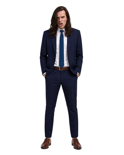 Man wearing a navy suit with a white shirt and brown shoes on a white background