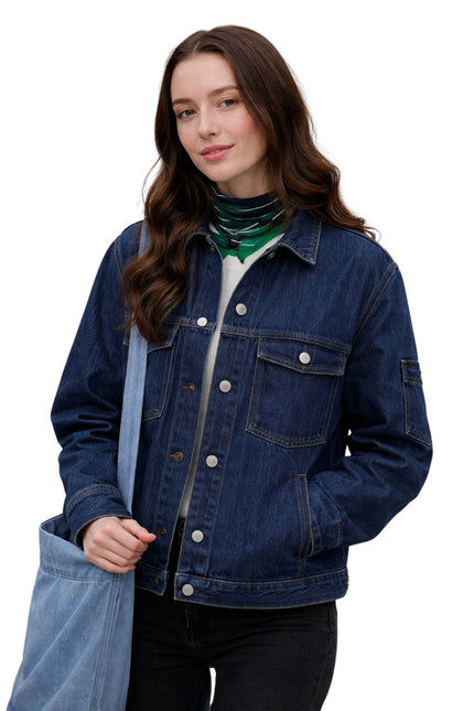 Woman wearing a blue denim jacket holding a blue tote bag on a white background