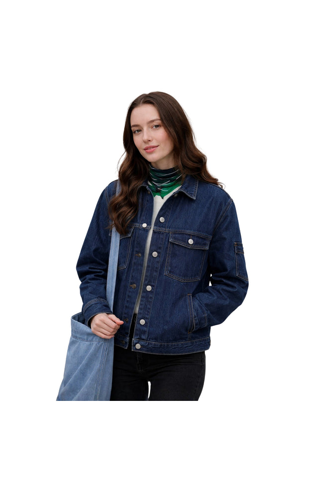 Woman wearing a blue denim jacket holding a blue tote bag on a white background