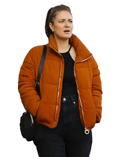 Woman wearing an orange quilted jacket on a white background