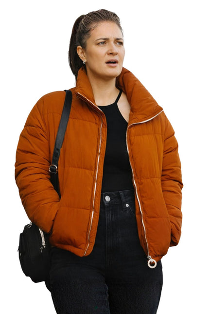 Woman wearing an orange quilted jacket on a white background