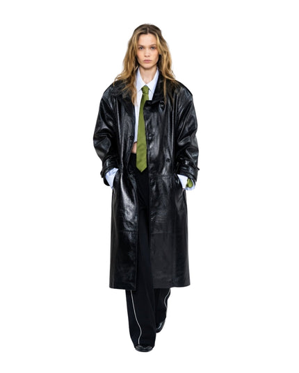Person wearing a long black coat and green tie on a white background