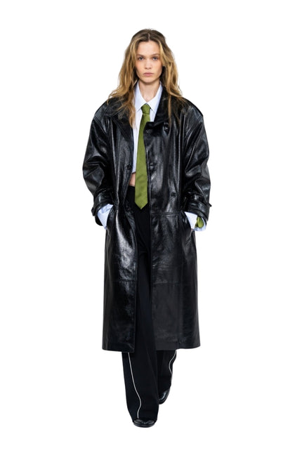 Person wearing a long black coat and green tie on a white background