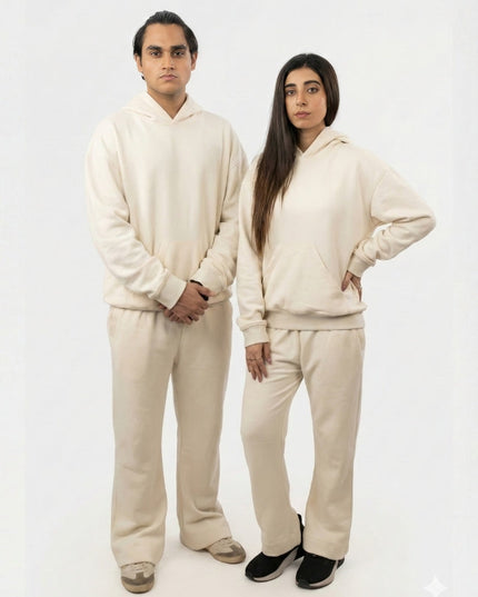 Two people wearing matching beige outfits on a white background