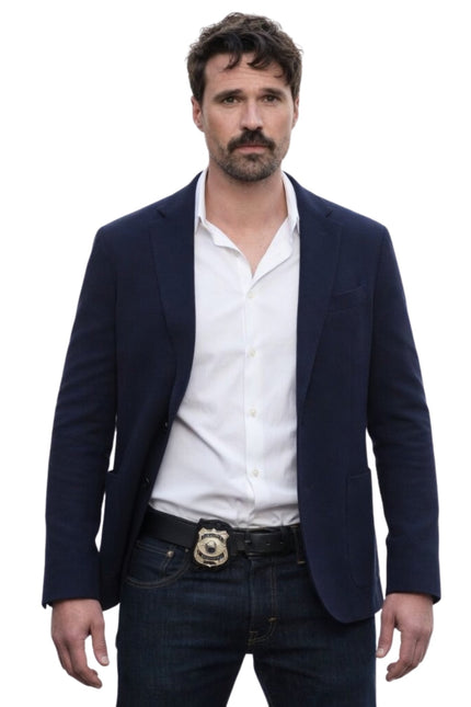 Man wearing a navy blazer, white shirt, and dark jeans on a white background