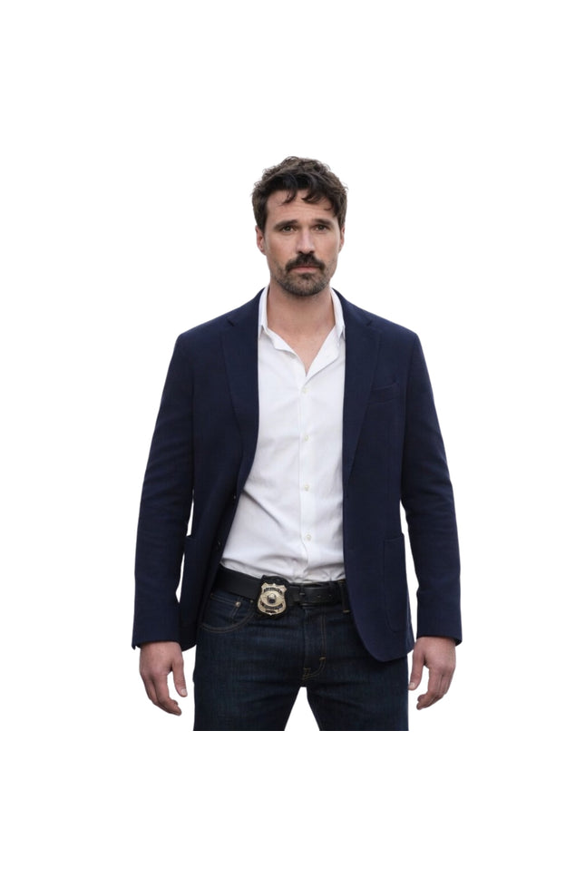Man wearing a navy blazer, white shirt, and dark jeans on a white background