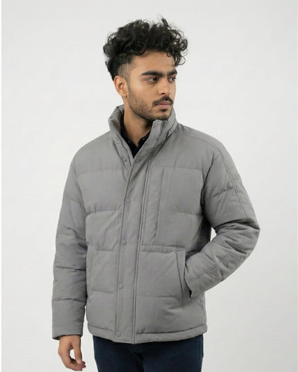 Man wearing a gray puffer jacket against a white background