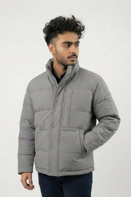 Man wearing a gray puffer jacket against a white background