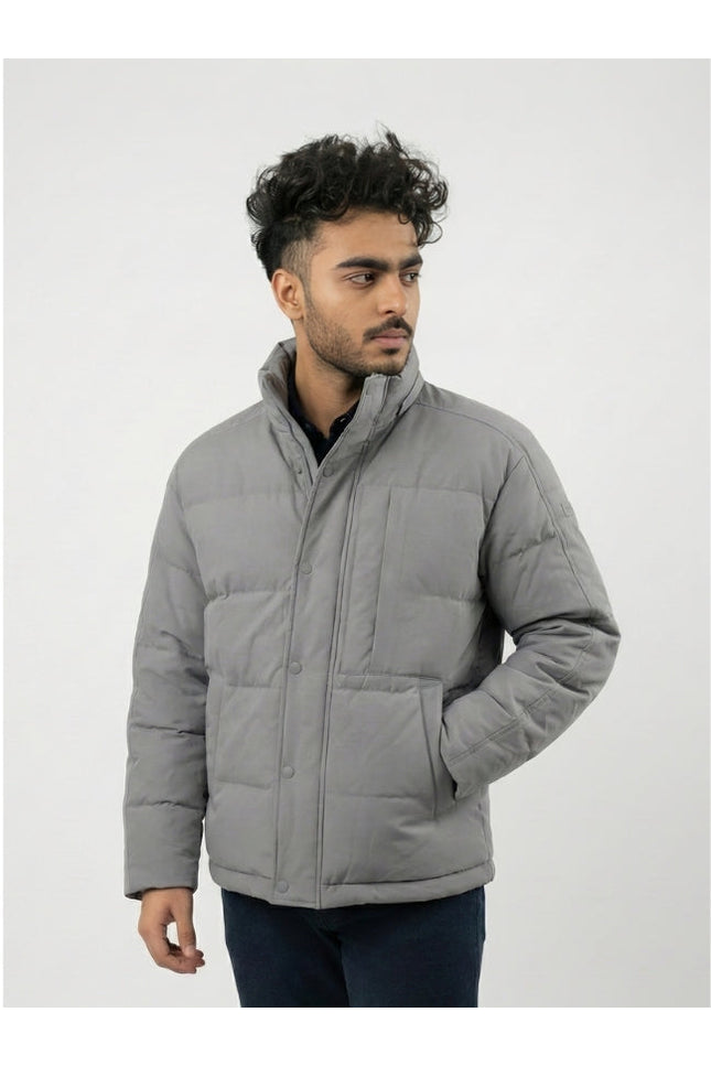 Man wearing a gray puffer jacket against a white background