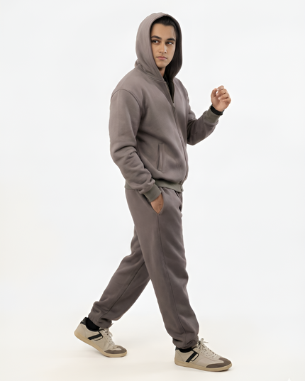 Person wearing a gray hoodie and pants on a white background
