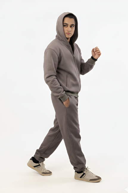 Person wearing a gray hoodie and pants on a white background