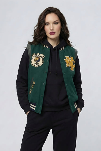 Woman wearing a green and black varsity jacket with logos on a light gray background