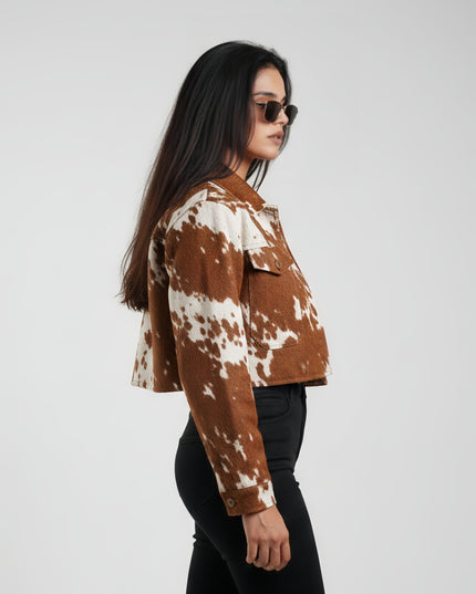 Woman wearing a brown and white cow print jacket on a white background