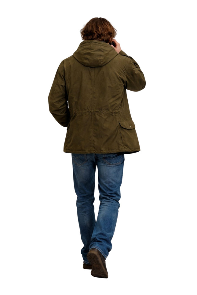 Person wearing a green jacket and blue jeans on a white background