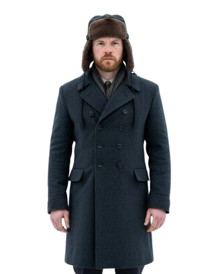 Man wearing a long dark coat and a fur-lined hat on a white background