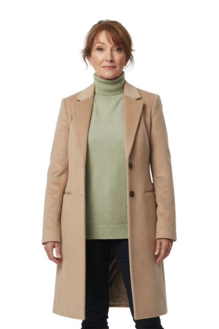 Woman wearing a beige coat over a green sweater on a white background