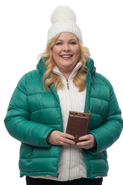 Person wearing a green puffer jacket and white beanie holding a brown book on a white background
