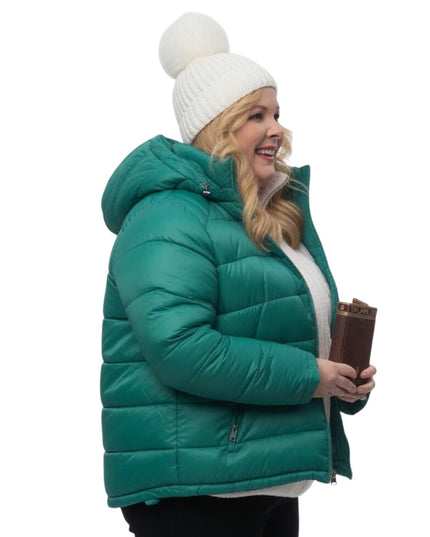 Woman wearing a teal puffer jacket and white beanie on a white background