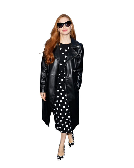 Woman wearing a black leather coat over a black and white polka dot dress on a white background