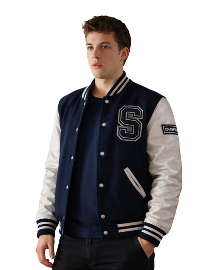 Man wearing a navy and white varsity jacket with a letter 'S' on a white background
