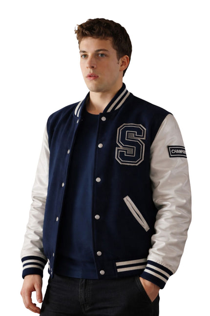 Man wearing a navy and white varsity jacket with a letter 'S' on a white background