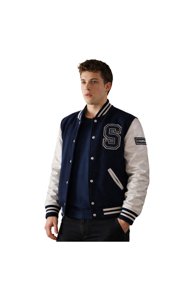 Man wearing a navy and white varsity jacket with a letter 'S' on a white background